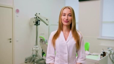 Ameliyattan önce dişçi muayenehanesinde duran güzel gülümseyen genç dişçinin portresi.