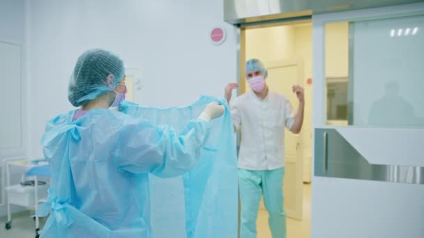 Verpleegster Helpt Chirurg Een Steriele Jurk Aan Trekken Voor Operatie — Stockvideo