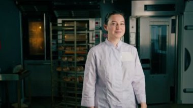 Üniformalı güzel kadın fırıncı işe başlamadan önce fırının yanında duruyor.