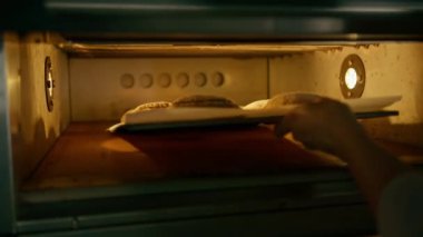 Profesyonel mutfağın fırınında çiğ ekmek tepsisi pişiriliyor.