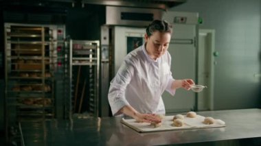 Konsantre güzel kadın fırıncı un serperek çiğ ekmeği süzer fırın pişirmeden önce taze hamur elde eder.