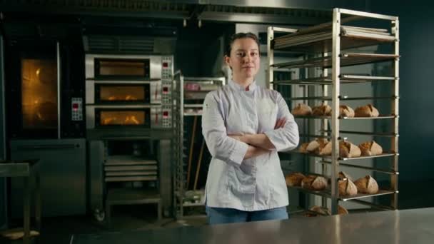 Пекарня Жінка Уніформі Біля Полиць Свіжоспеченим Хлібом Виглядає Камерою Посміхається — стокове відео