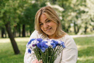 Elinde bir buket çiçekle sunulan bukete gülümseyen ve sevinen güzel hamile bir kadının portresi.