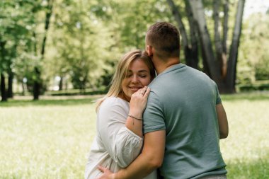Birbirine aşık bir çiftin portresi. Bir erkek ve hamile bir kadın sarılıyor, mutlu bir aileye yeni birinin katılmasını bekliyorlar.