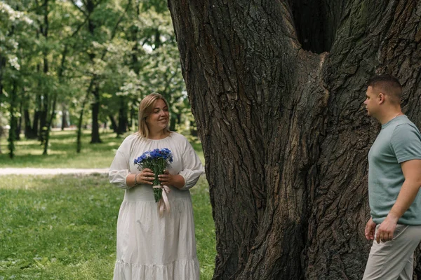 Πορτρέτο Μιας Ευτυχισμένης Εγκύου Ένα Φόρεμα Που Κρατά Λουλούδια Περπατώντας — Φωτογραφία Αρχείου