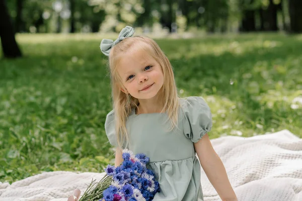 在公园里休息的一个快乐的小女孩的肖像 她带着鲜花无忧无虑地度过了童年的夏日 — 图库照片