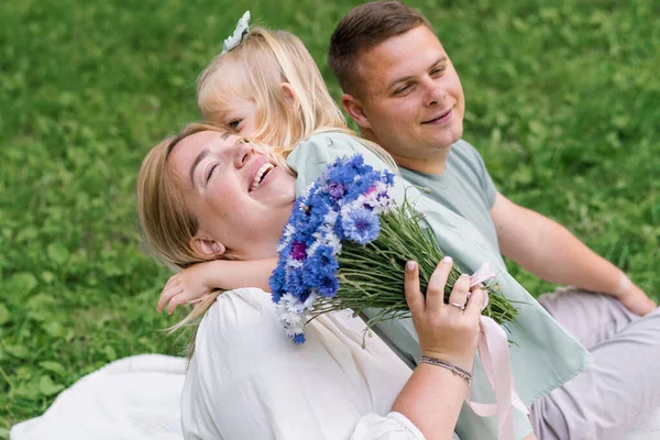 公園の自然の中で幸せな家族は ドレスの小さな娘が彼女の母の花束を与える — ストック写真