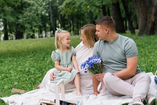 快乐的家庭在公园里休息着 在大自然的庇佑下 庆祝小朋友的生日 一束鲜花拥抱着孩子 — 图库照片