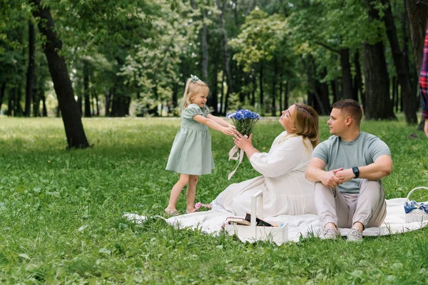 행복한 가족은 공원에서 자연에서 드레스에 그녀의 어머니 꽃다발을 제공합니다 — 스톡 사진