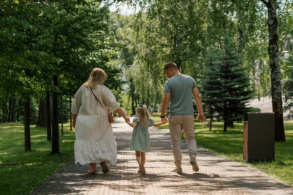 穿着绿色夏装的可爱小女孩 和父母一起在城市公园里散步夏季家庭生活幸福的家庭后视镜 — 图库照片