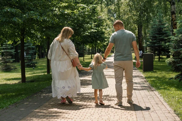穿着绿色夏装的可爱小女孩 和父母一起在城市公园里散步夏季家庭生活幸福的家庭后视镜 — 图库照片