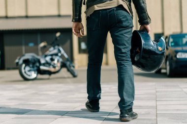 Vahşi motorcu yarış başlamadan önce siyah motosiklete biner ve elinde bir kaskla hız tutkusu tutar.