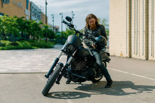 ひげを持つ残酷な赤毛のバイカーは レースの開始前に黒いオートバイに座って スピードのために彼の手の渇きを保持しています — ストック写真