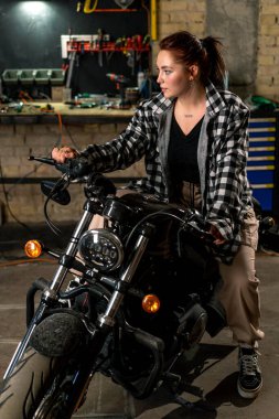 Yaratıcı, otantik motosiklet atölyesi. Güzel, genç bir motosikletli kız.