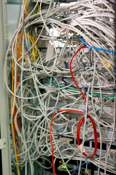 close-up of a pile of network patch cables sorted in a rack cabinet leading from a patch panel in server rack in a data center room