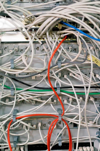 データセンター ルーム内のサーバー ラックのパッチ パネルから導く棚のキャビネットでソートされたネットワーク パッチ ケーブルのパイルのクローズアップ — ストック写真