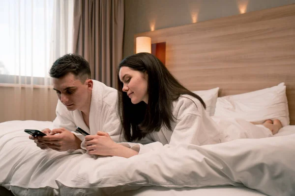 young couple in the room of a luxury hotel room people hold smartphones in their hands do not communicate with each other travel