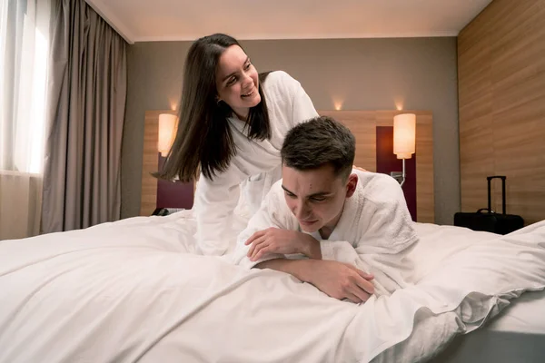 portrait young couple on honeymoon in hotel room lying bed in white robes flirting laughing happy lovers