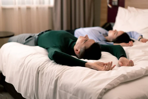 young couple in the room of a luxury hotel room lovers fall on the bed raise their hands to top rear view travel concept