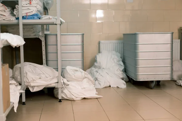 ホテルの汚れたベッドリネンの産業洗濯は洗濯機の清潔さおよびおもてなしの概念に荷を積まれる前に分類される床にあります — ストック写真