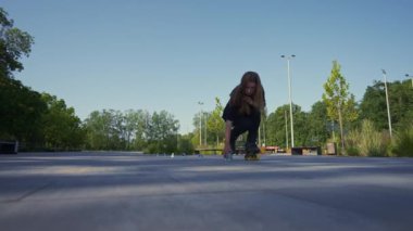 Parkta paten kayan kız şehrin arka planında aktif kız konileri eritiyor sokak sporu konseptini sergiliyor.