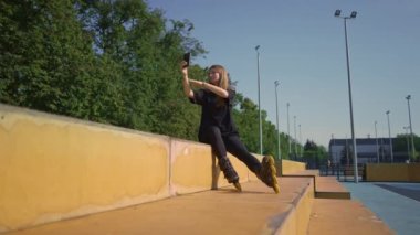 Spor sahasında paten kayan sporcu kız, dersten memnun, telefon caddesinde aktif spor yaşam tarzında kendi fotoğrafını çekiyor.