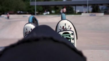 Bir kaykay parkının arka planında patenlerin yakın planında bir sokak sporcusu yarışmadan sonra dinleniyor.