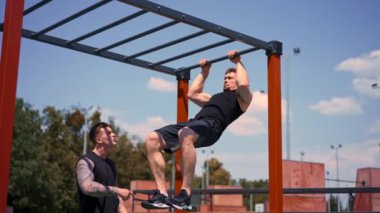 Kişisel fitness antrenörü veya vücut geliştirme eğitmeni spor sahası motivasyon desteği veren genç bir sporcuyu eğitir.