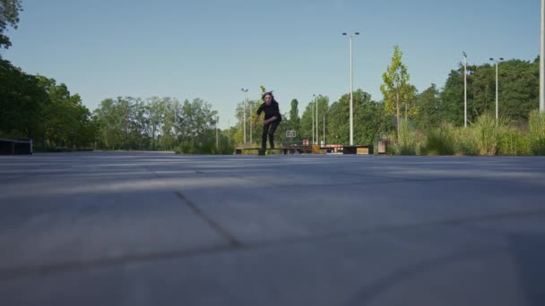 スポーティガールは 街の背景に公園でローラースケートに乗ります アクティブガールは ローラースケートレッスンストリートスポーツコンセプトを楽しんでいます — ストック動画