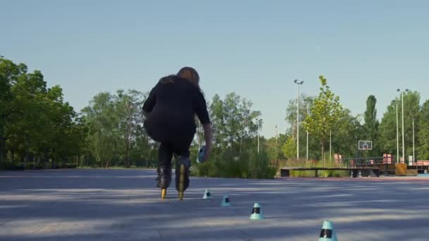 スポーティガールは 都市アクティブガールメルトコーンの背景にある公園でローラースケートです トリックストリートスポーツコンセプトを実行します — ストック動画