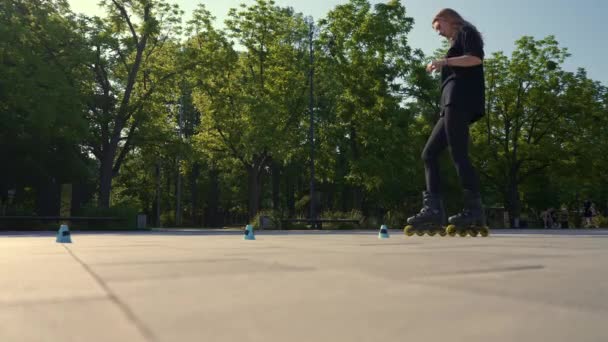 スポーティガール トリック パークシティバックのローラースケート ローラースケートレッスンを楽しむ ストリートスポーツのコーンで近い — ストック動画