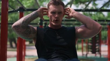 Genç kaslı sporcu vücut geliştirici sokak sporu sahasında yakın çekim sırasında karın egzersizi yapıyor.