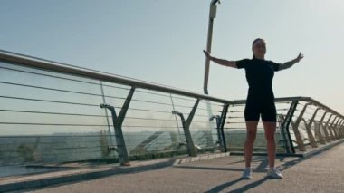 Fitness genç sporcu kız sabah ısınma egzersizleri yapıyor. Şehirdeki köprüdeki spor salonunda antrenmandan önce.
