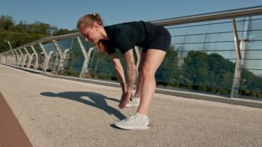 Fitness genç sporcu kız sabah ısınma egzersizleri yapıyor. Şehirdeki köprüdeki spor salonunda antrenmandan önce.
