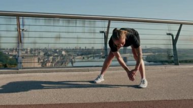 Fitness genç sporcu kız sabah ısınma egzersizleri yapıyor. Şehirdeki köprüdeki spor salonunda antrenmandan önce.