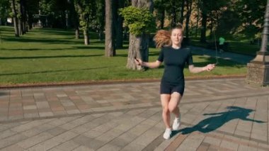 Spor salonundaki sporcu kız, sabah dövmeli, spor atlama halatı yapıyor, şehirde sağlık parkında egzersiz yapıyor.