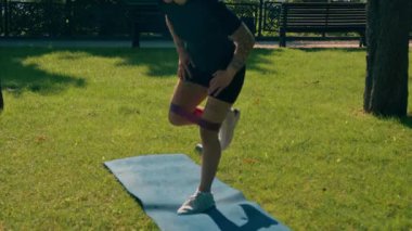 Genç sporcu kız spor minderinde egzersiz yapıyor. Bacaklarında lastik bantlarla parkta sağlıklı yaşam tarzı konseptiyle.