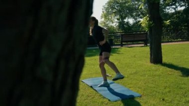 Genç sporcu kız spor minderinde egzersiz yapıyor. Bacaklarında lastik bantlarla parkta sağlıklı yaşam tarzı konseptiyle.