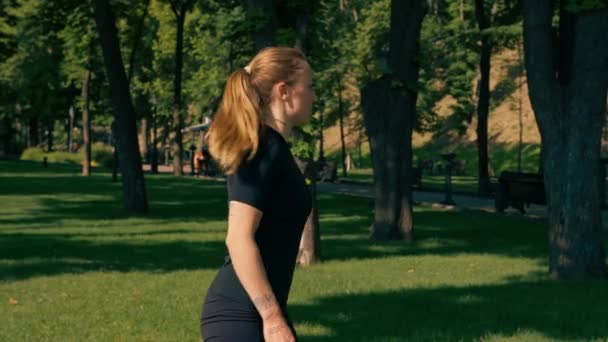 年轻的女运动员在运动垫上做体育锻炼 腿上绑着橡皮筋 进行公园外健康生活方式的概念 — 图库视频影像