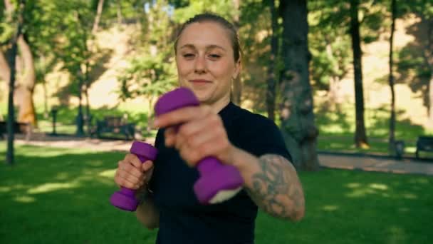 在公园健康生活理念的运动中 一个年轻的 心满意足的女运动员在室外用哑铃做运动的肖像 — 图库视频影像