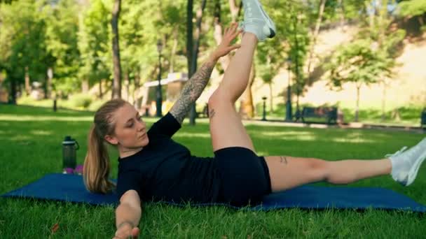 一个年轻的运动女孩在室外的运动垫上做腹部运动的肖像 同时在公园里锻炼健康的生活方式概念 — 图库视频影像