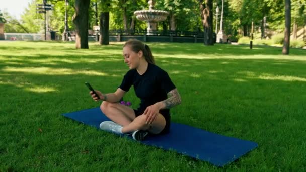 Spor Minderinde Elinde Akıllı Bir Telefonla Parkta Dinlenen Genç Bir — Stok video