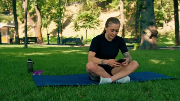 Spor Minderinde Elinde Akıllı Bir Telefonla Parkta Dinlenen Genç Bir — Stok video