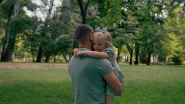 Mutlu bir aile. Genç bir baba kucağında bir çocuk. Babası ve kızı parkta birbirlerine sarılıyorlar.