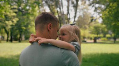 Mutlu bir aile. Genç bir baba kucağında bir çocuk. Babası ve kızı parkta birbirlerine sarılıyorlar.