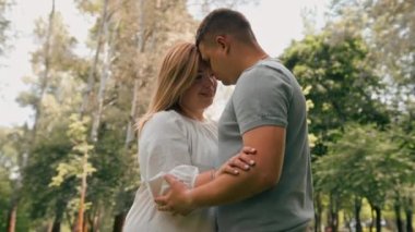 Birbirine aşık bir çiftin portresi. Bir erkek ve hamile bir kadın sarılıyor, mutlu bir aileye yeni birinin katılmasını bekliyorlar.