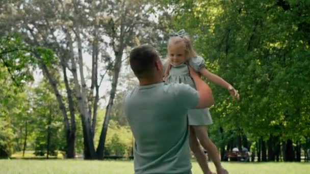 公園で子供と遊ぶ父親は子供と遊ぶ空の幸せな家族の日ファミリーで娘を投げます — ストック動画