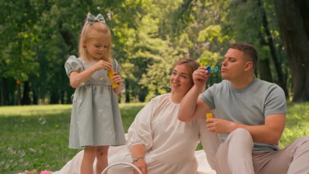 快乐的家庭在公园里放松一下爸爸和女儿吹泡泡肥皂泡快乐的童年家庭周末 — 图库视频影像