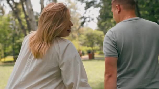 恋をしているカップルの肖像画 男と妊娠中の女性 カップルは 幸せな家族に新しい追加を待っている手を握って公園を歩きます — ストック動画