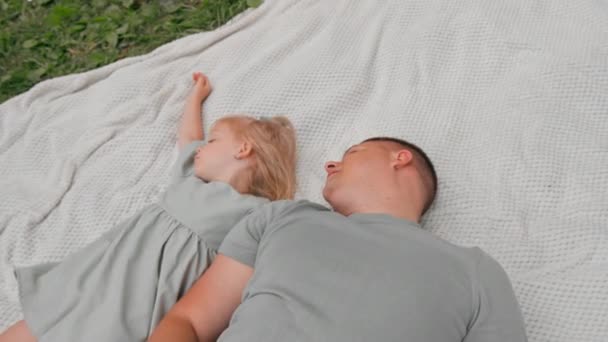 幸せな家族の若い父親は公園で娘と横たわっています 幸せな家族 屋外でリラックスする父の日 — ストック動画